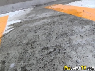Asian pees behind car in public car park